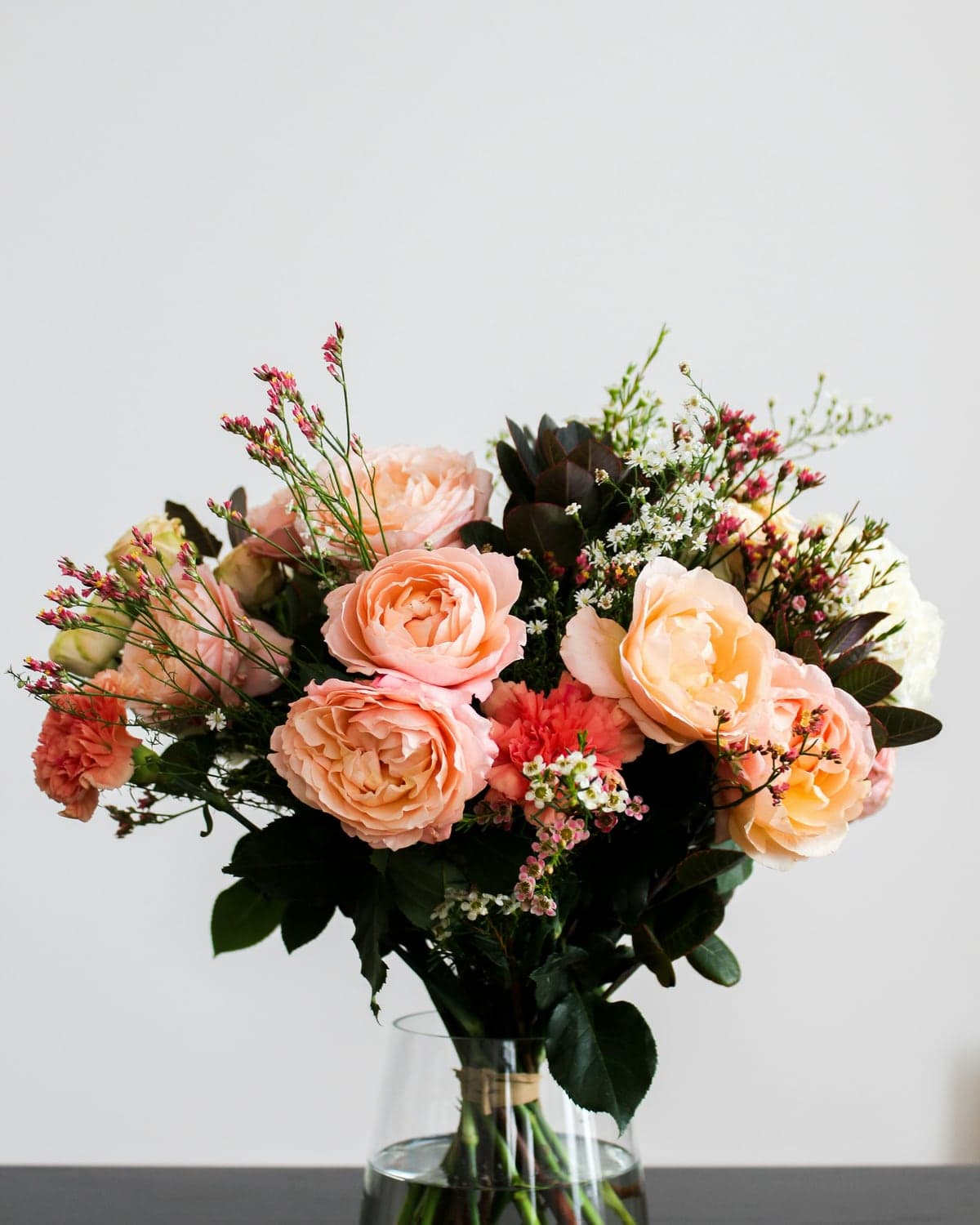Peach and coral roses arranged in a clear glass vase